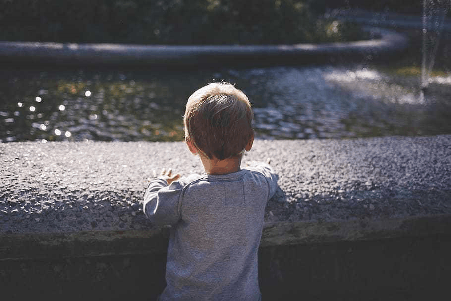 A naive child playing with himself in a garden unaware of what's going to happen